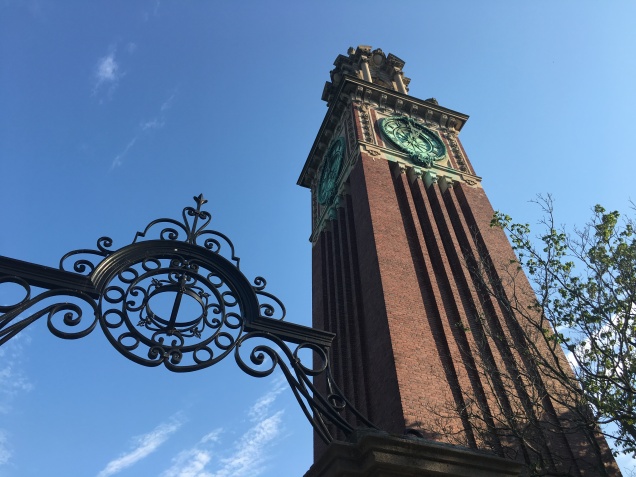 The gate entrance stands below the memorial clock tower built on campus grounds.
